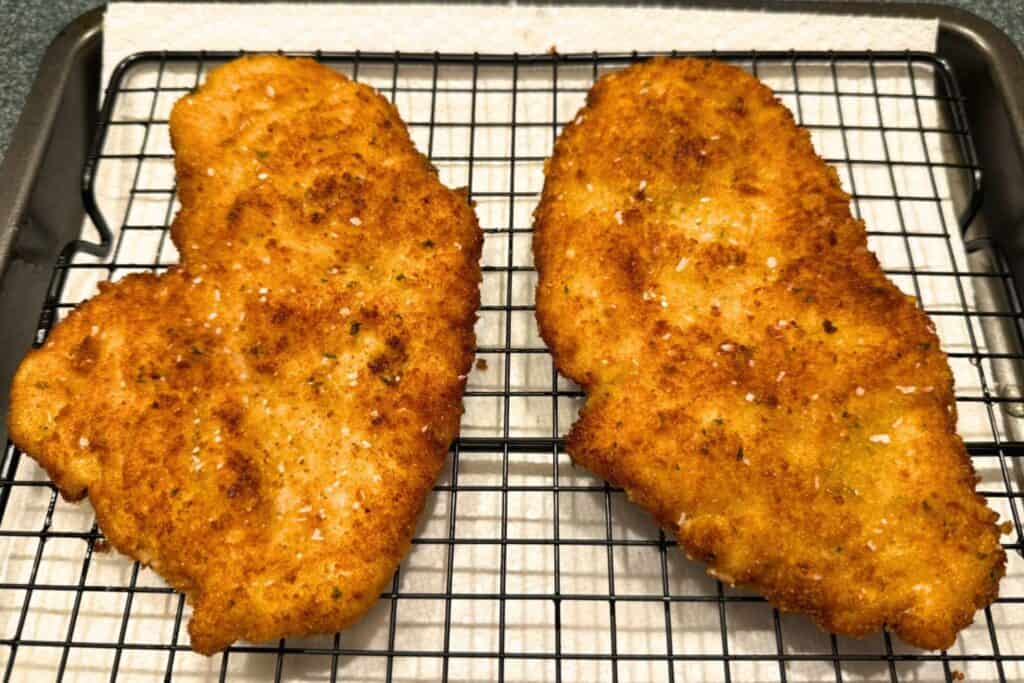Fried chicken cutlets resting on a cooling rack