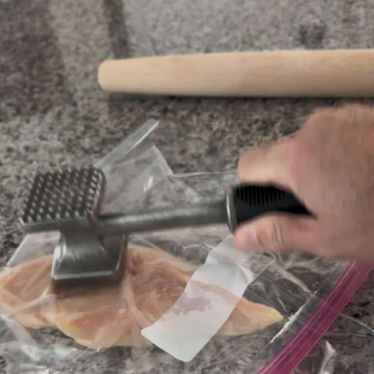 Demonstrating how to flatten chicken breast using a meat tenderizer