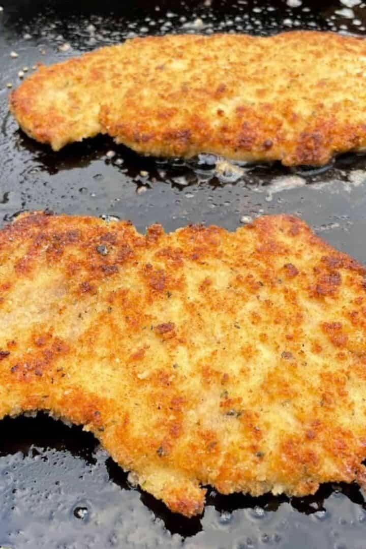 Breaded chicken cutlets cooking on a Blackstone griddle