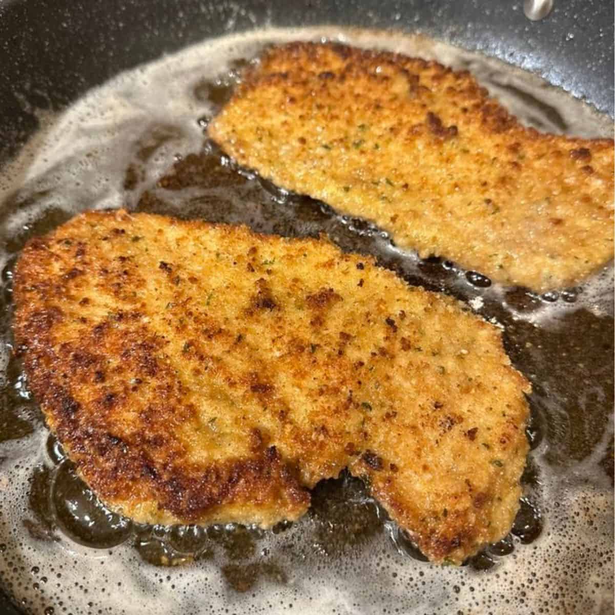 Italian breaded chicken cutlets frying in a pan