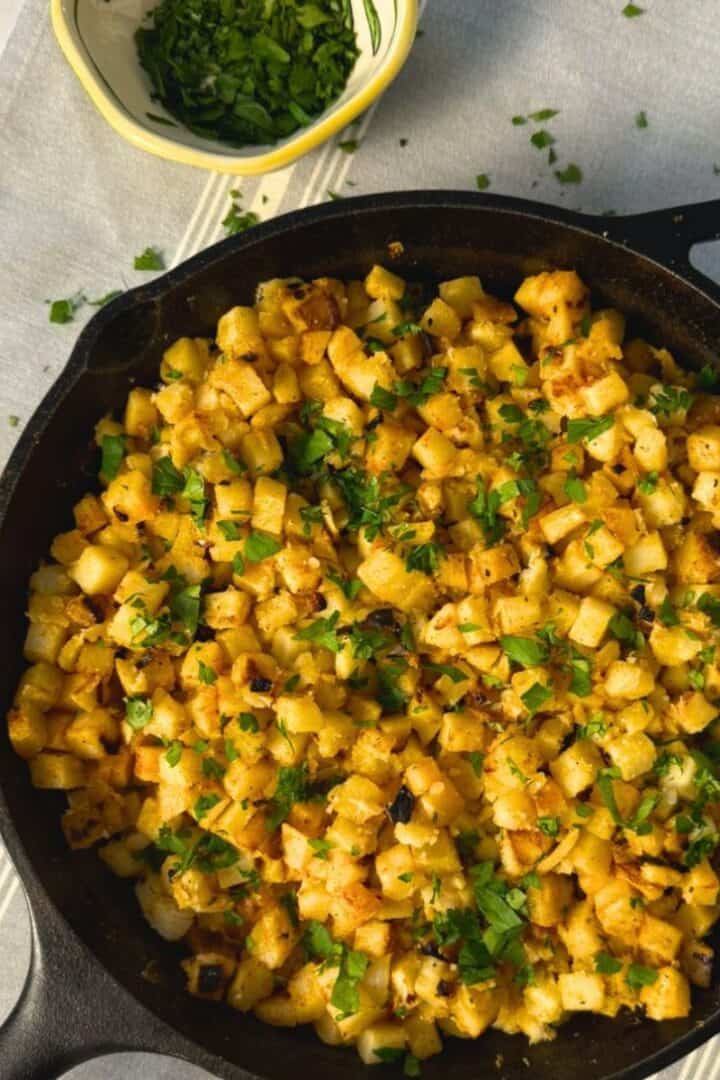Cast iton pan full of crispy breakfast potatoes made with frozen hash browns