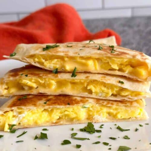 A cheesy breakfast quesadilla cut into thirds and stacked on a white plate