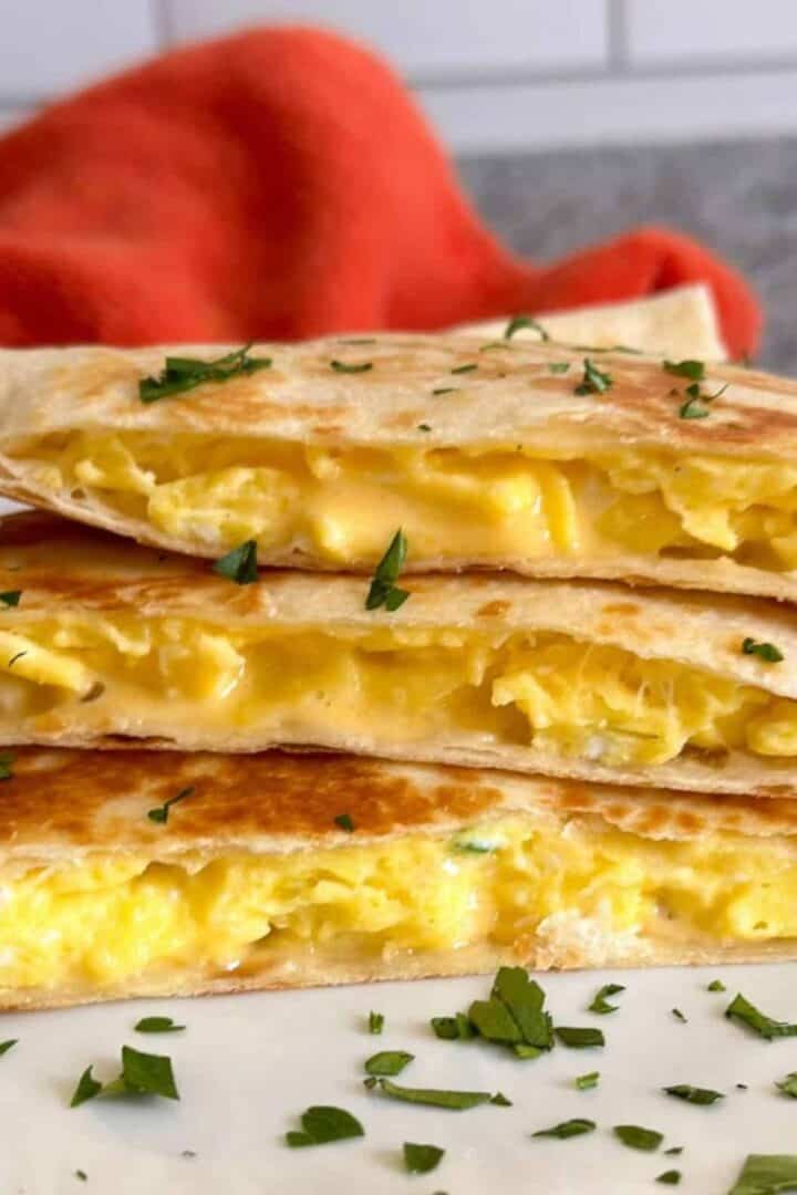 A cheesy breakfast quesadilla cut into thirds and stacked on a white plate