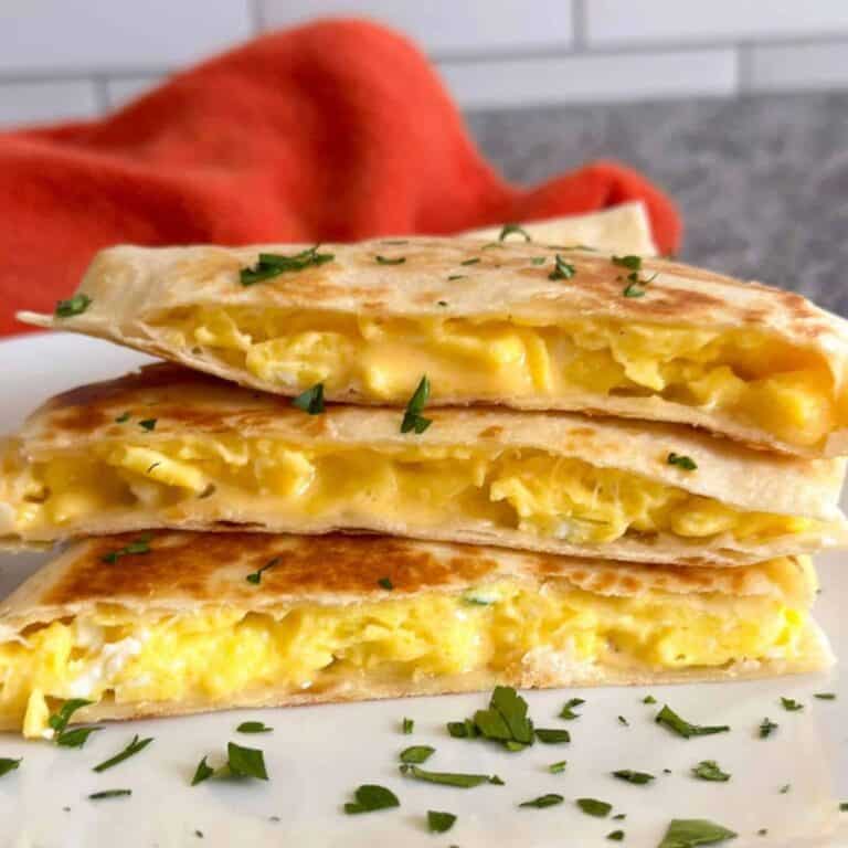 A cheesy breakfast quesadilla cut into thirds and stacked on a white plate