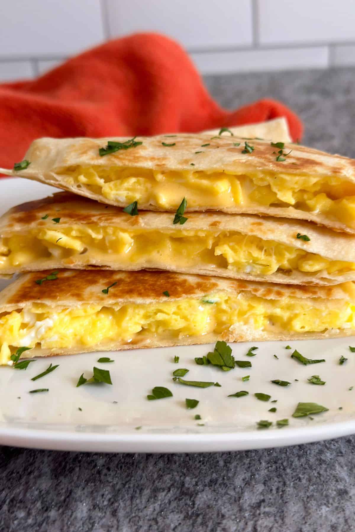 A cheesy breakfast quesadilla cut into thirds and stacked on a white plate