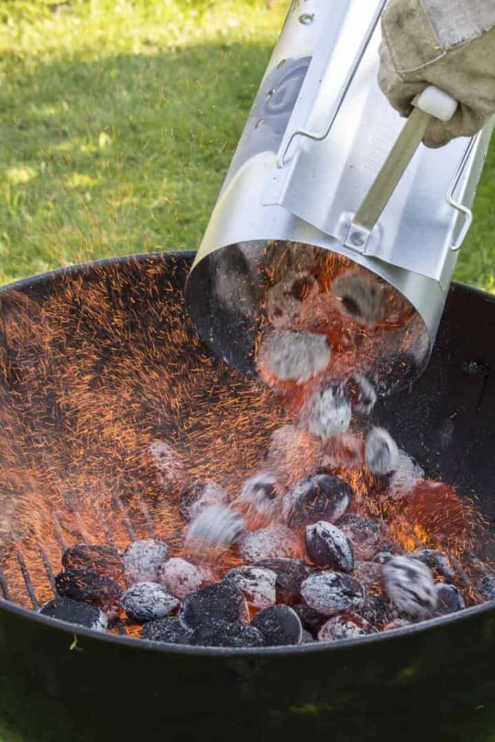 Pouring lit charcoal from a chimney into a grill