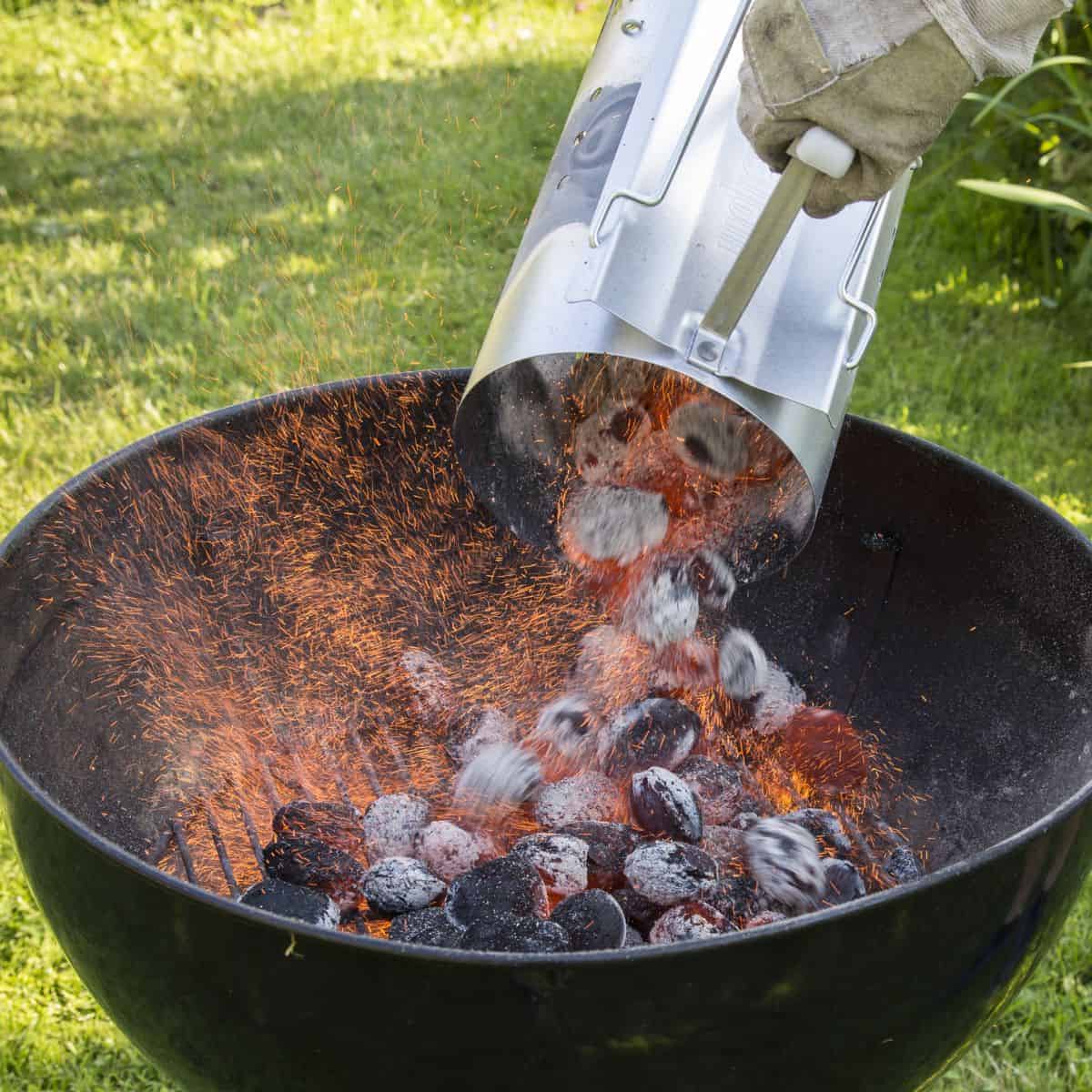 Pouring lit charcoal from a chimney into a grill