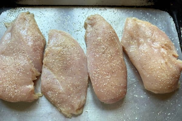 Four raw chicken breasts seasoned