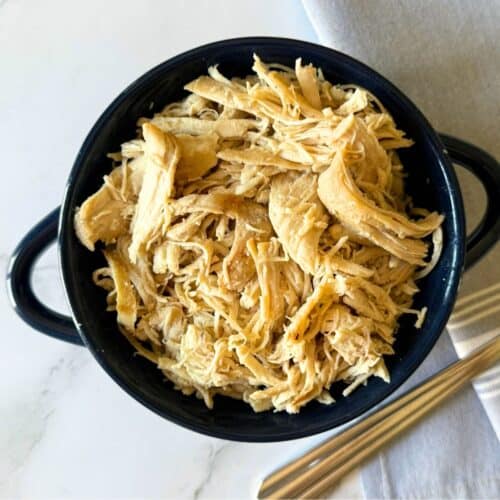 Small blue bowl full of shredded chicken