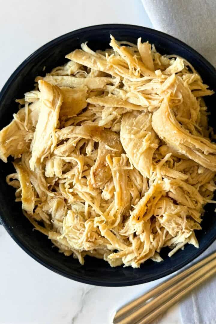 Small blue bowl full of shredded chicken