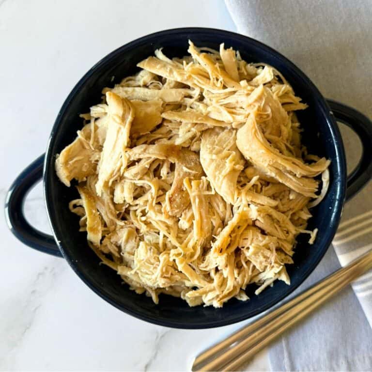 Small blue bowl full of shredded chicken