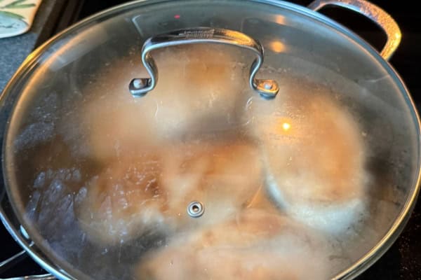 Covered pan of chicken breast cooking