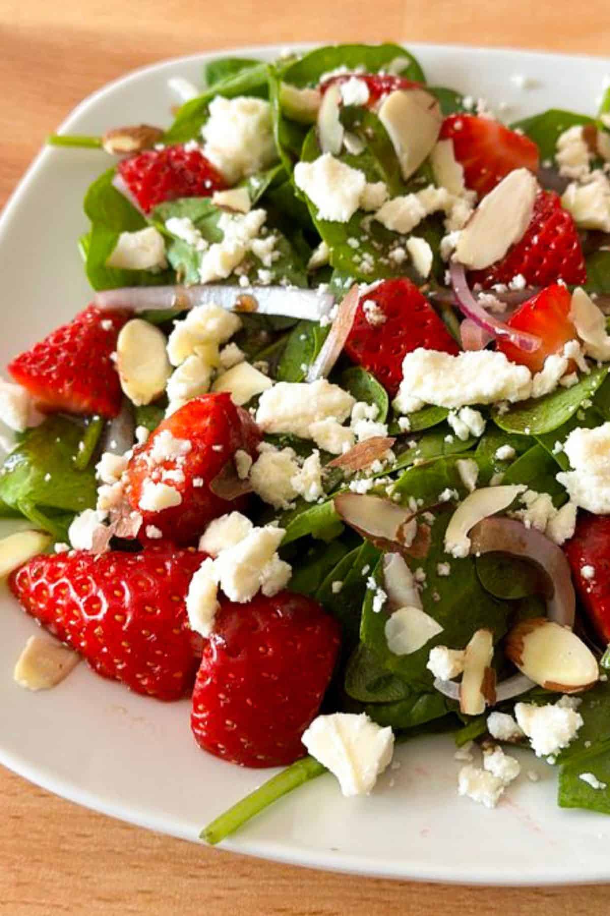 Strawberry spinach salad with feta cheese on a white plate