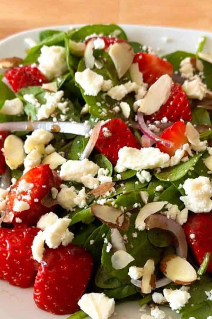 Strawberry spinach salad with feta cheese on a white plate