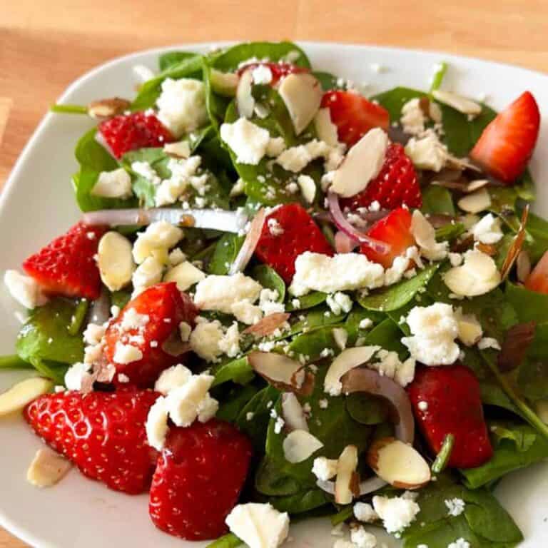 Strawberry spinach salad with feta cheese on a white plate