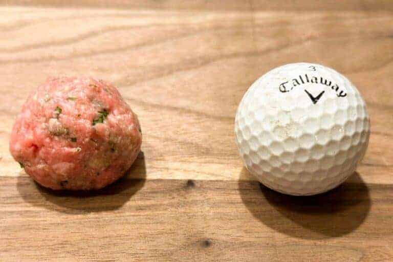 A Swedish meatball next to a gold ball to compare size
