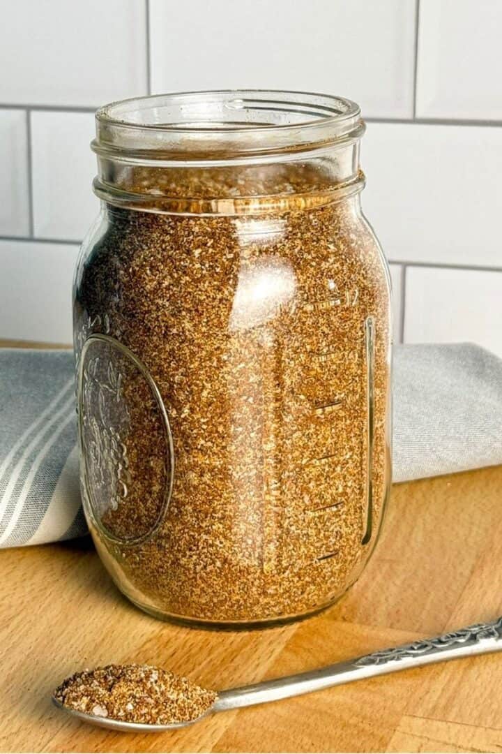 A glass jar and spoon of homemade sweet and smoky rub