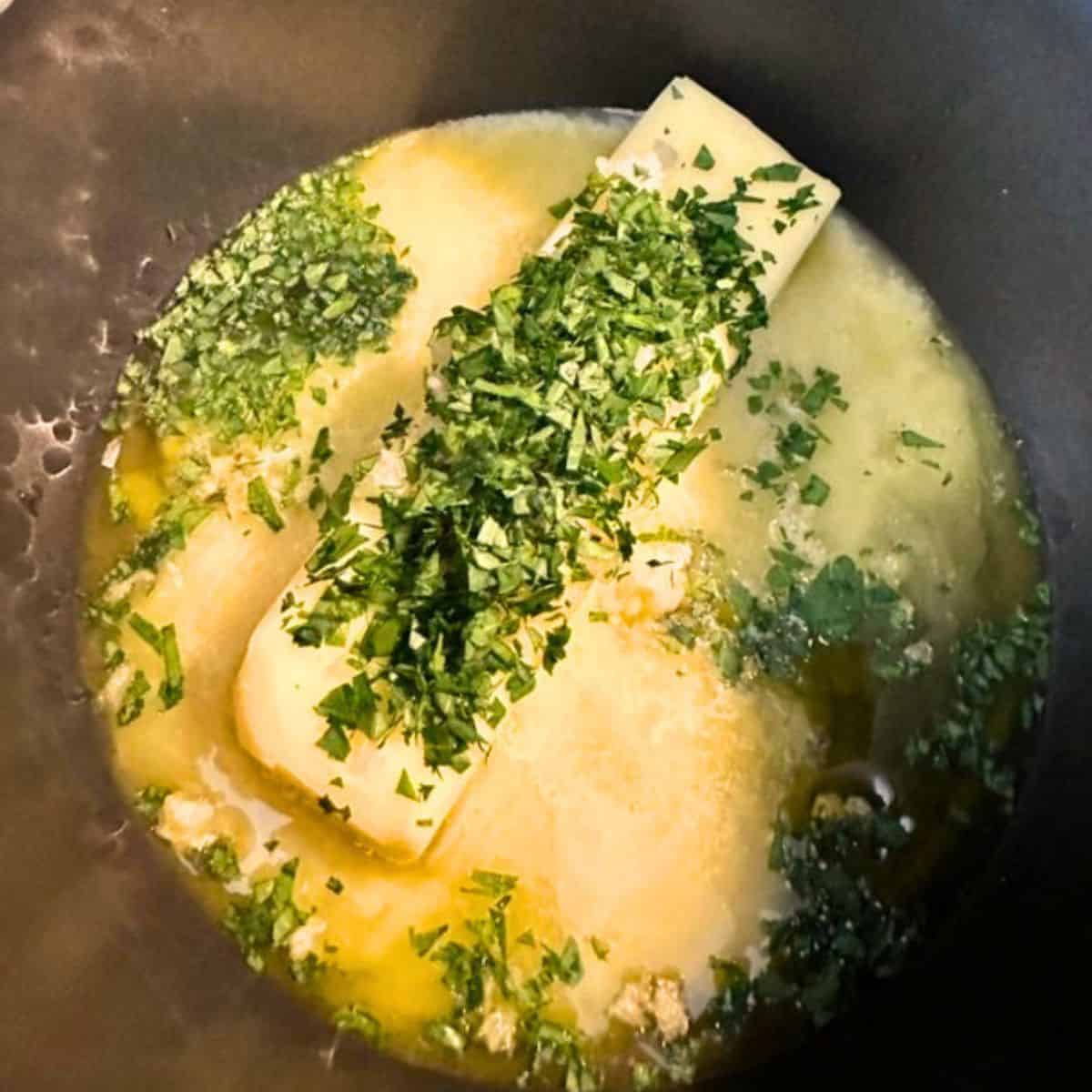 Butter, garlic, and herbs melting in a pot to make my turkey injection recipe