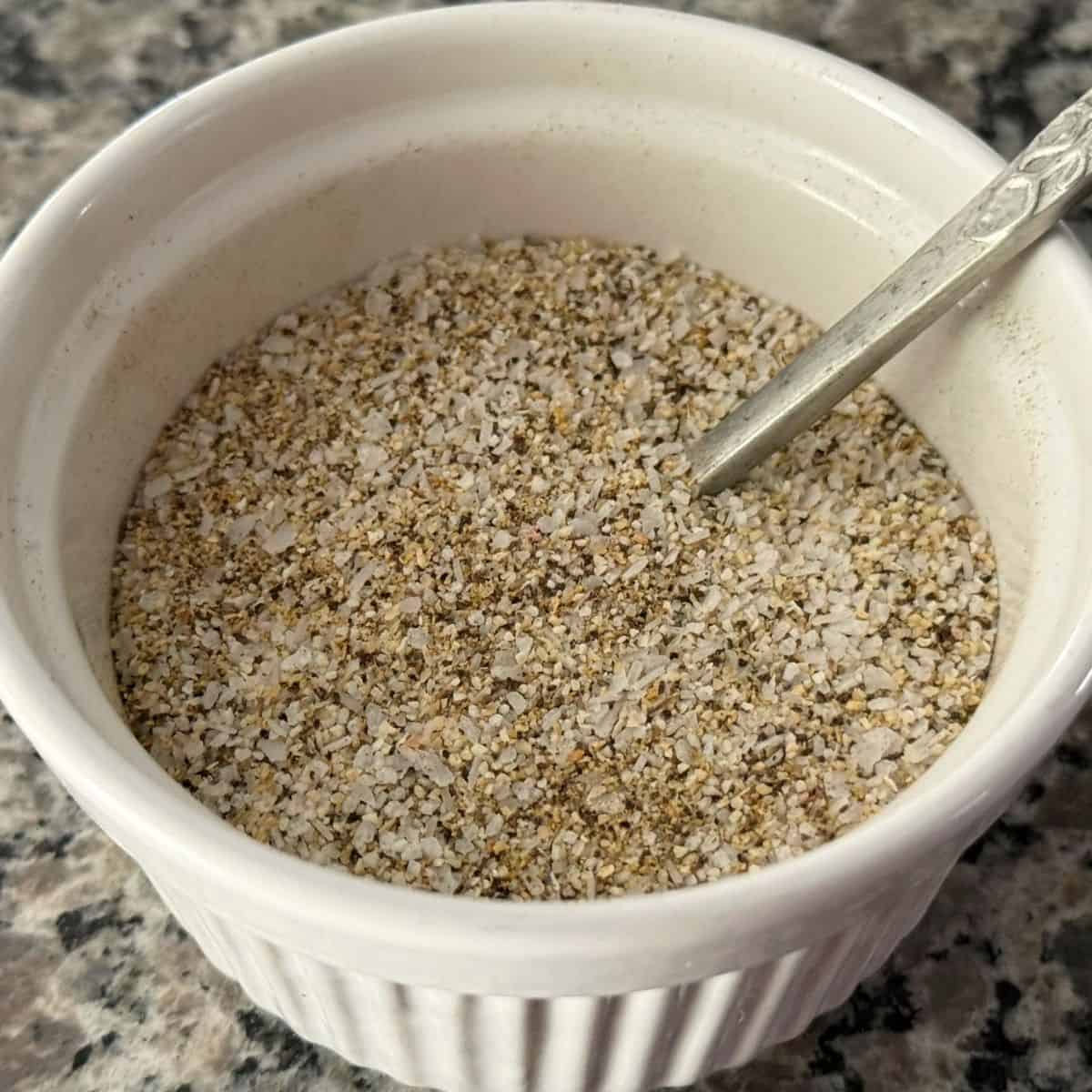 White bowl full of my Core Four blend of seasoning with a silver spoon