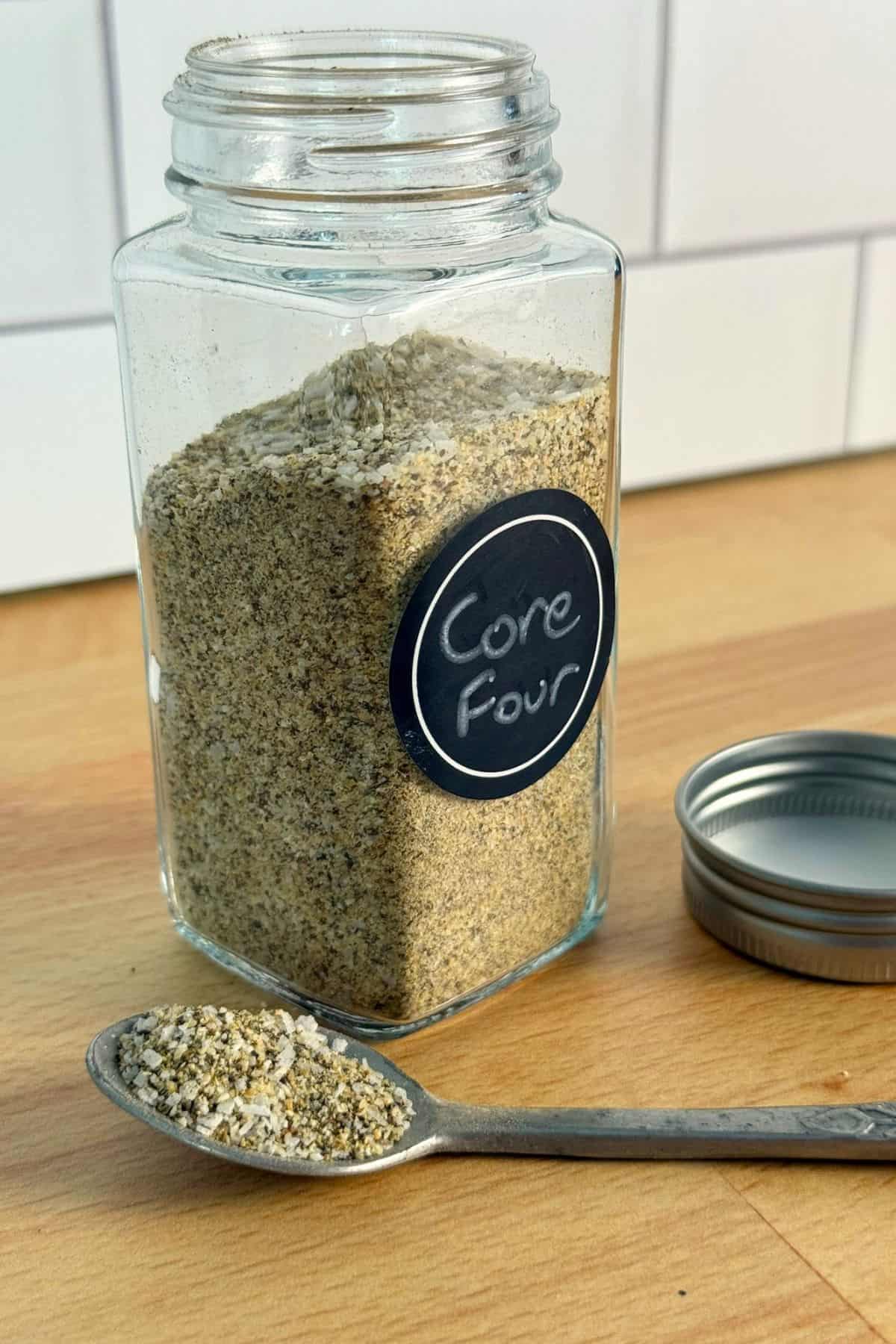 Spice jar full of Core Four rub on the kitchen counter with a spoon full of rub