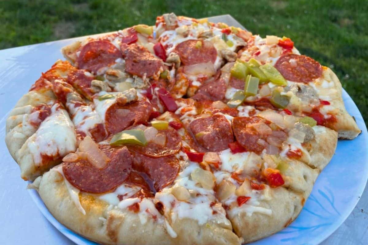 Frozen pizza supreme cooked outside on a griddle