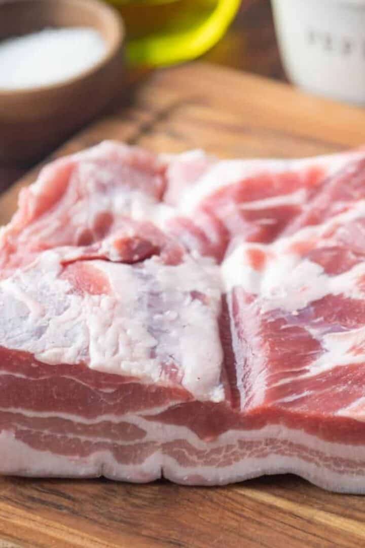 Thick slab of pork belly on a wooden cutting board