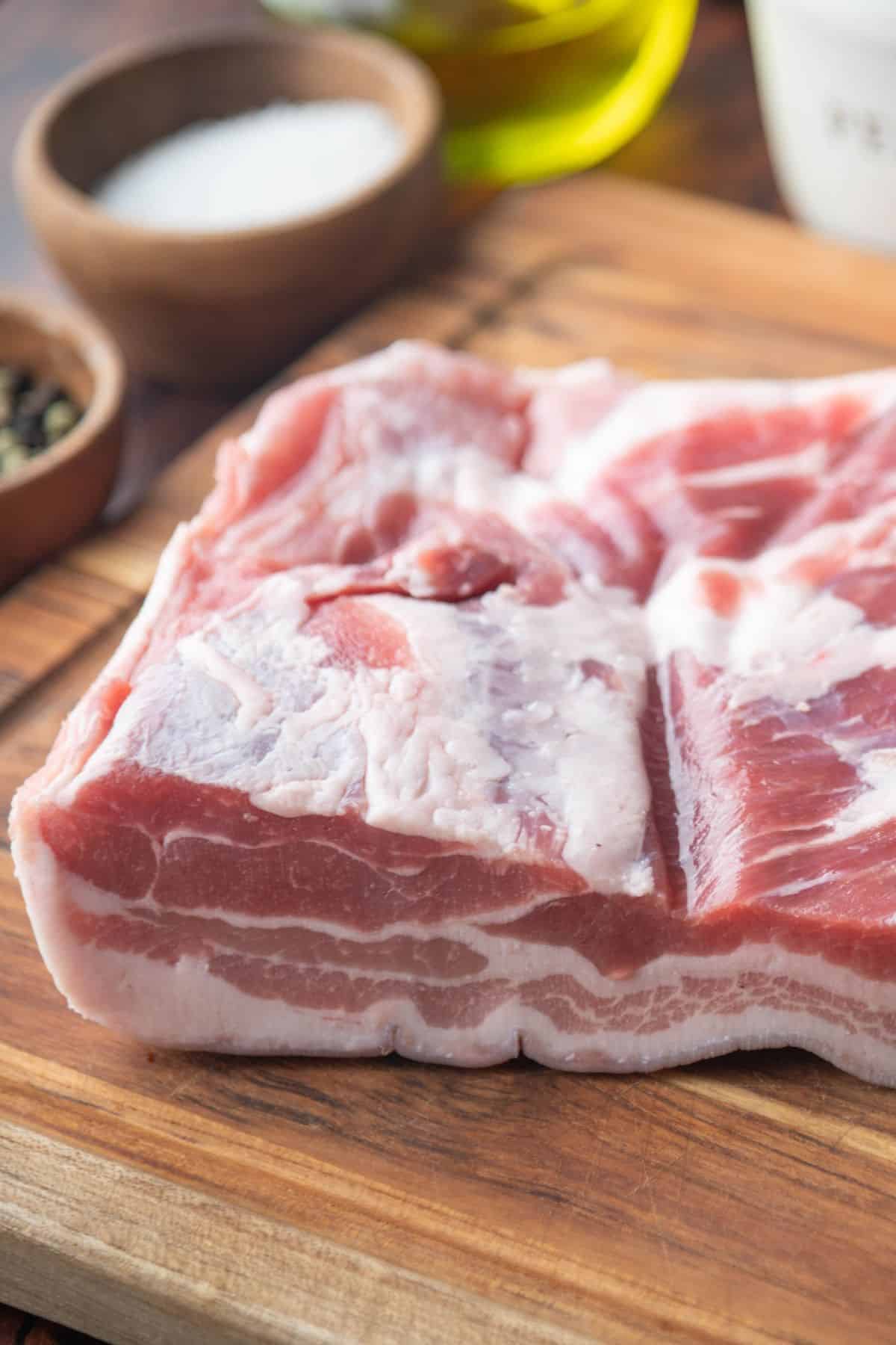 Thick slab of pork belly on a wooden cutting board