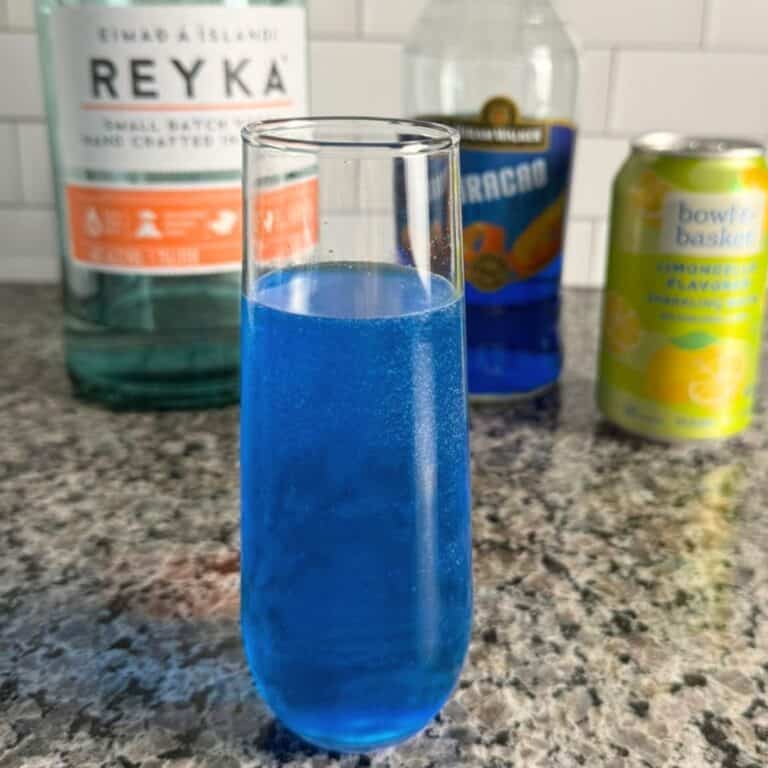 A Star Trek inspired glass of bright blue "Romulan Ale" and the ingredients lined up behind it