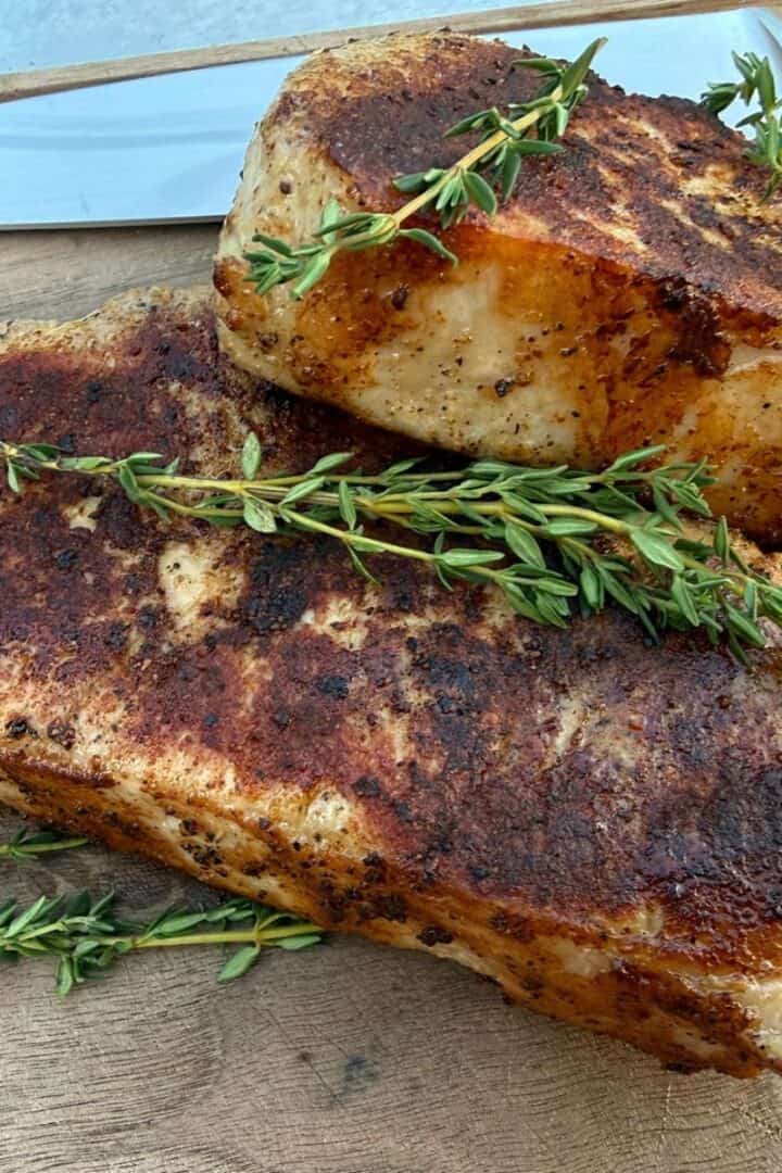 Two sous vide pork chops on a cutting board with a chef knife