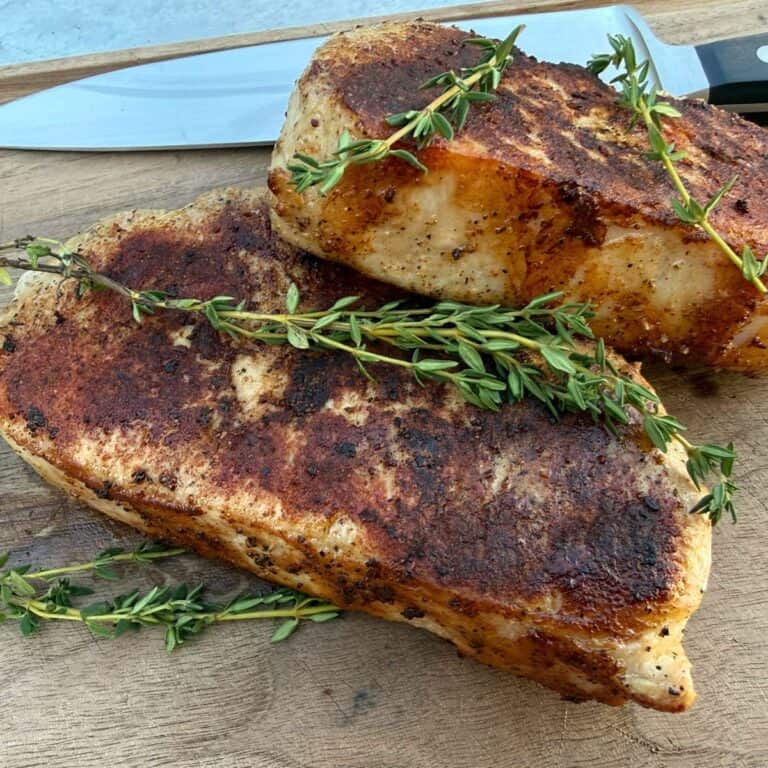 Two sous vide pork chops on a cutting board with a chef knife