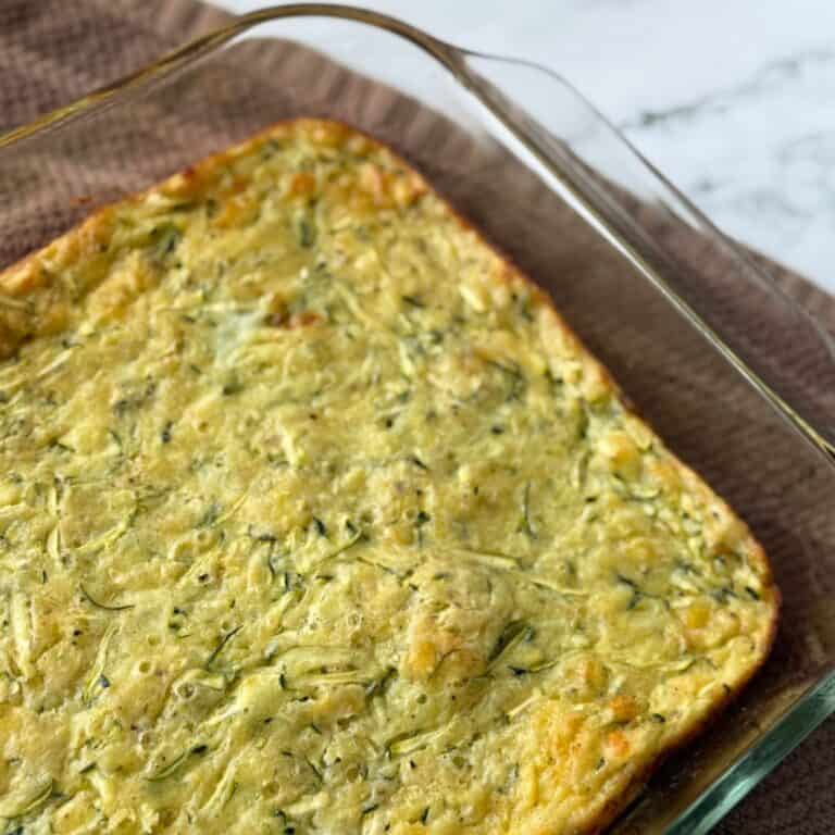 A baked zucchini pie fresh out of the oven and cooling in a glass baking dish