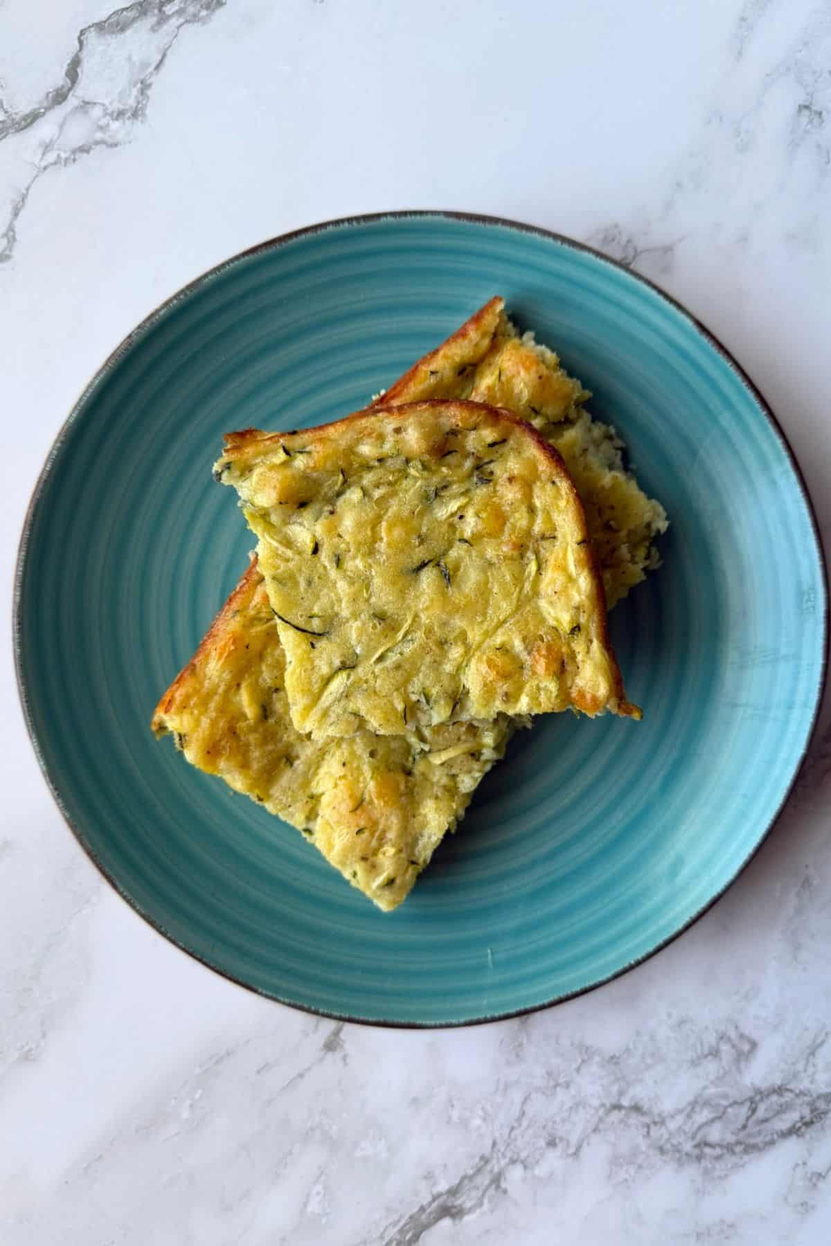 Three slices of zucchini pie on a blue plate