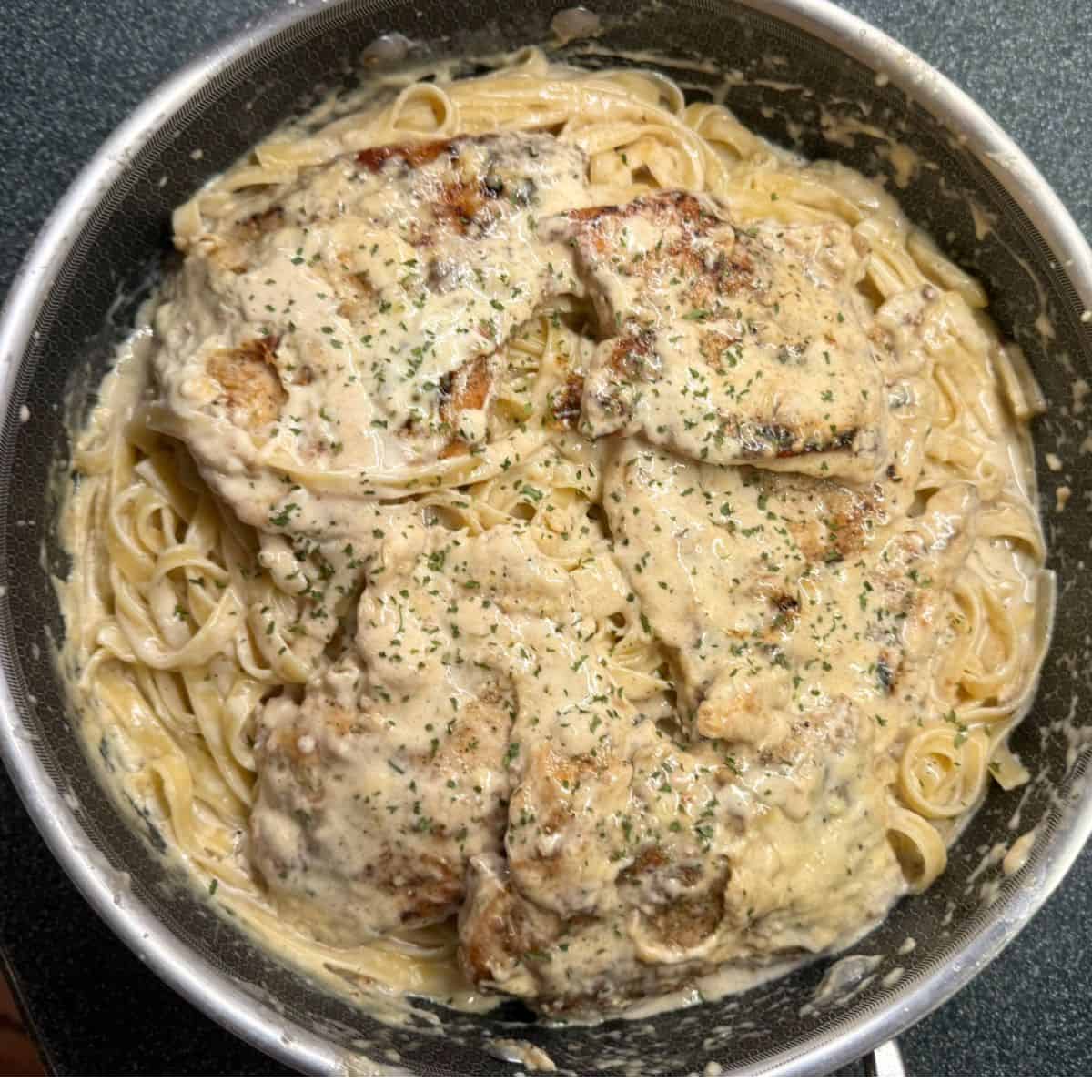 Creamy Garlic Chicken in a pan with fettucine pasta