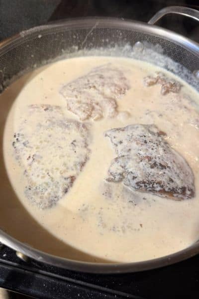 Creamy garlic chicken cooking in a pan