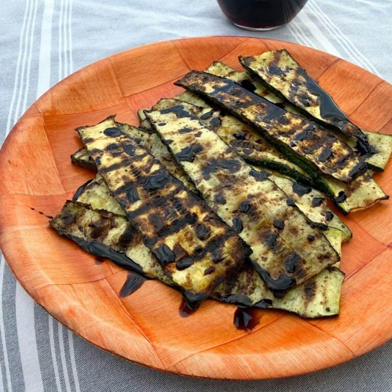 Grilled zucchini on a wooden plate and drizzled with balsamic glaze