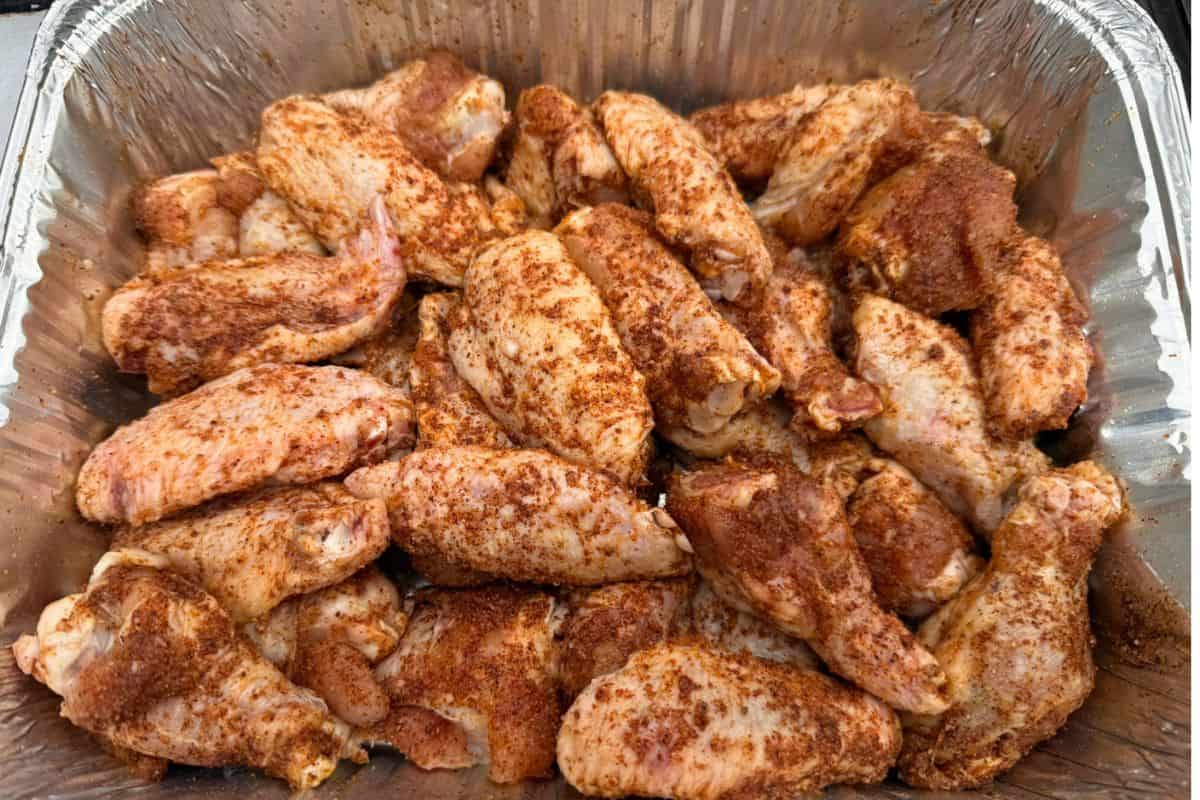 Aluminum pan full of rubbed chicken wings ready for the grill or oven.