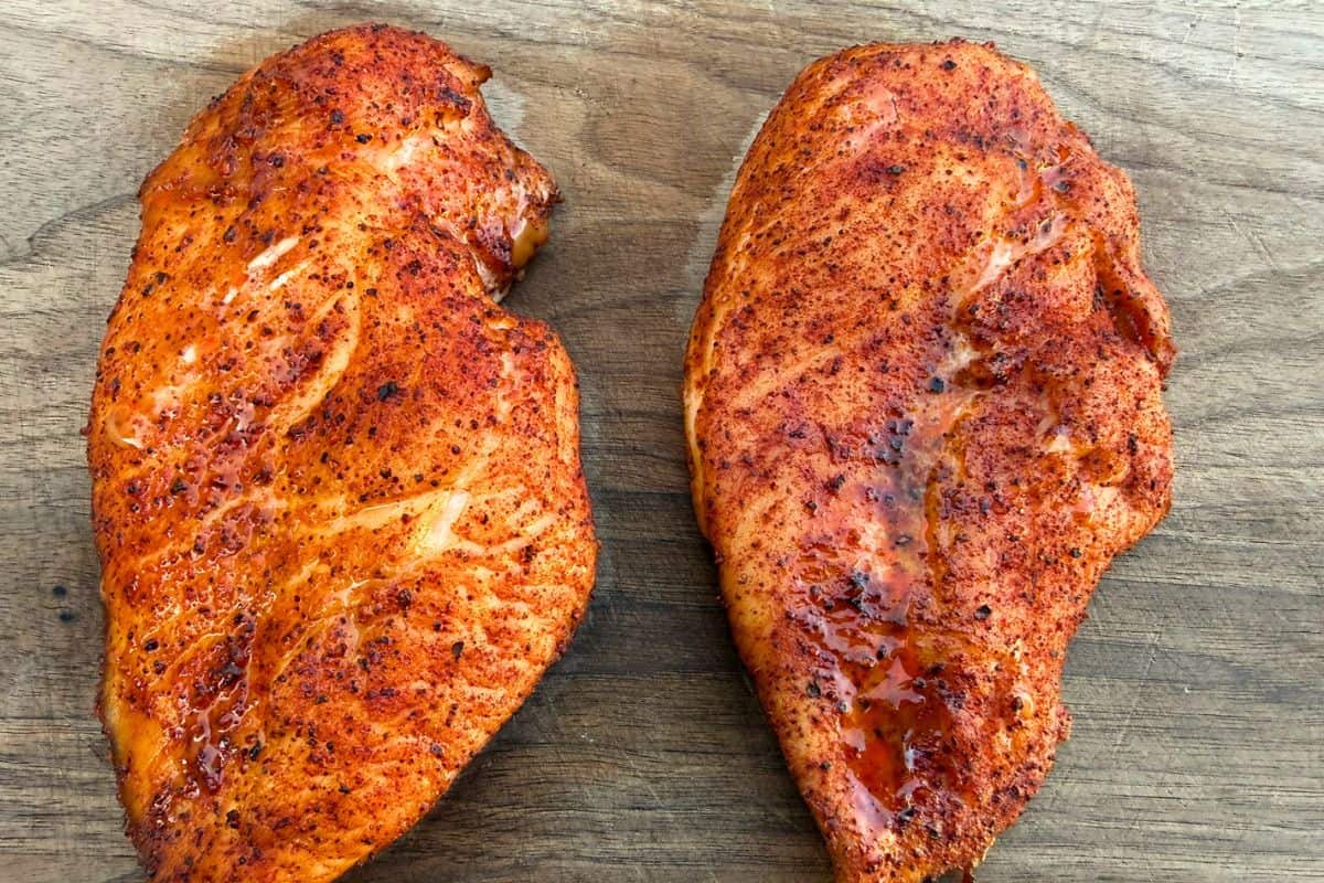 Two smoked chicken breasts on a wood cutting board